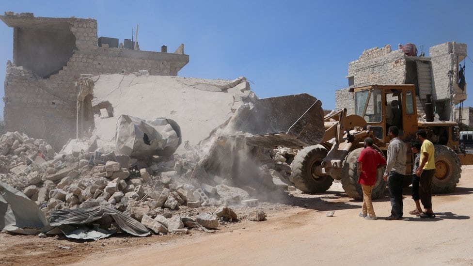 Buldožer čisti ruševine nakon vladinog bombardovanja pobunjenika koji su držali grad Urum al-Kubra