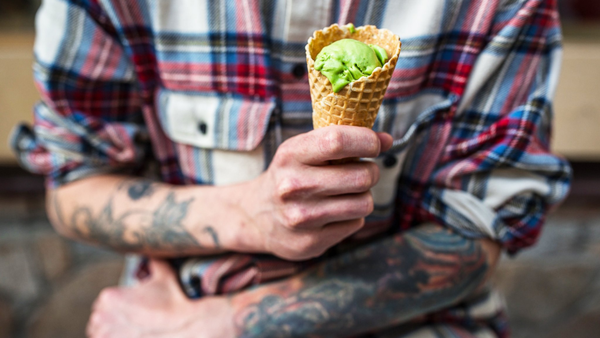 Slava sitting outside his cafe, Fika, holding a green matcha flavoured ice cream in a cone