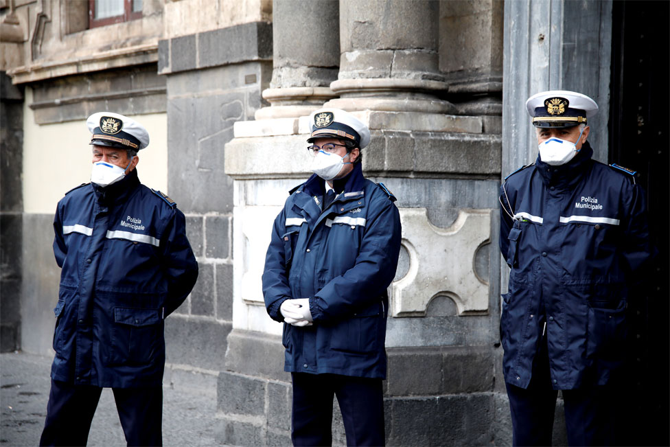 Three policemen stand in a line wearing face masks