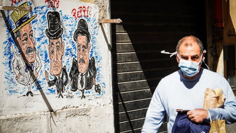 A person wearing a protective face mask walks at Quartieri Spagnoli, Naples, Italy, 18 March 2020