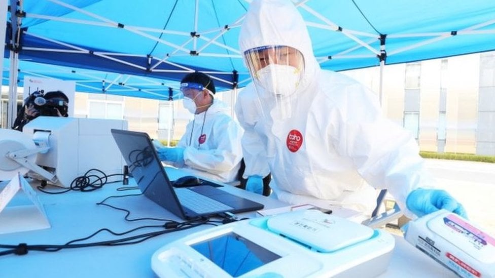 Personnel wearing PPE is seen managing a polling station outside a medical centre in South Korea