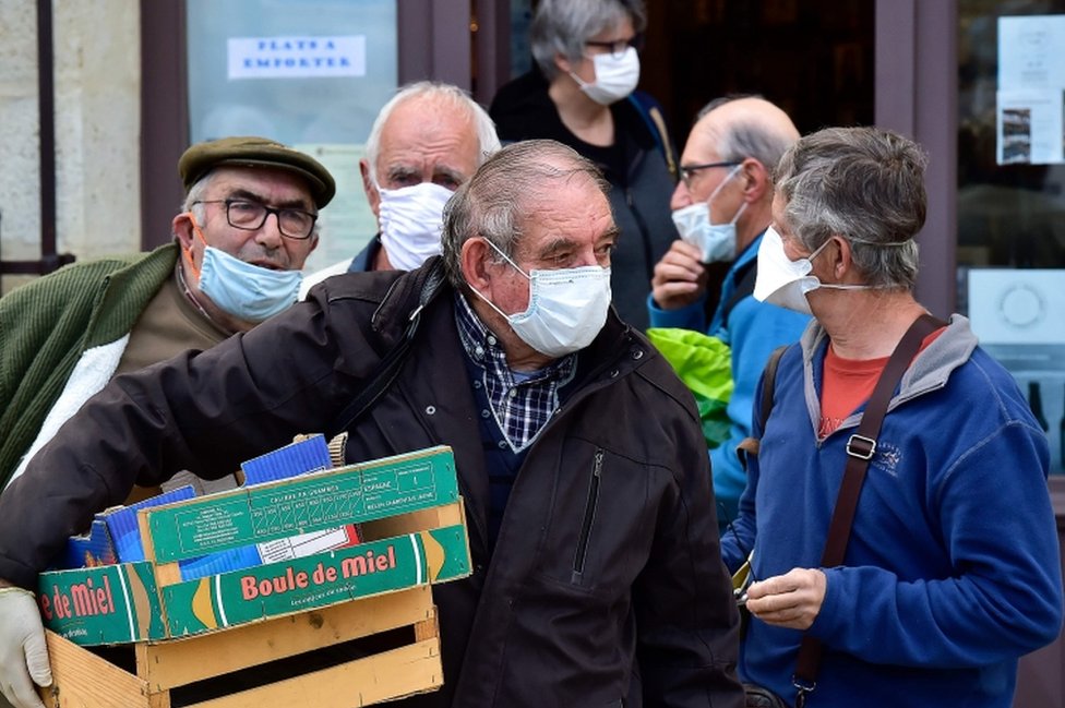 Wearing protective face masks, shoppers wait for their turn to enter the Cadillac market near the French city of Bordeaux on April 25, 2020