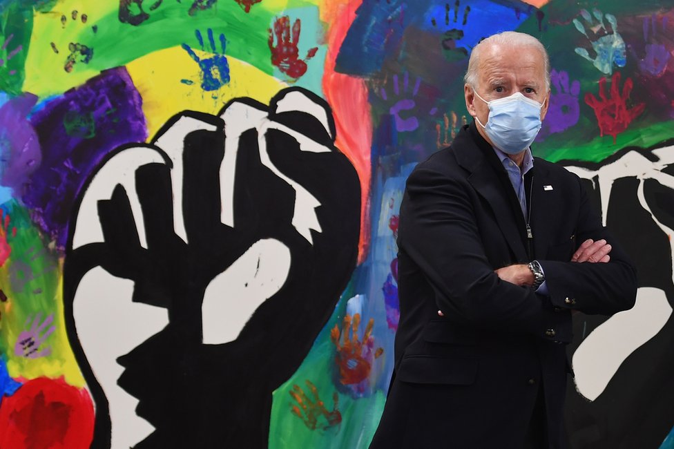 Joe Biden in front of a colourful wall mural