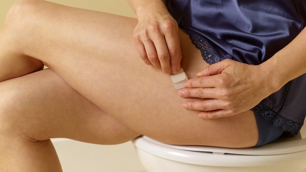 Hormonal Replacement Therapy - woman applying a patch on her leg.