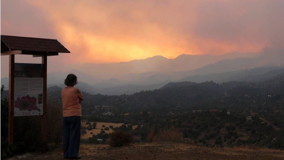 A woman looks at the smoke and fire from the fire