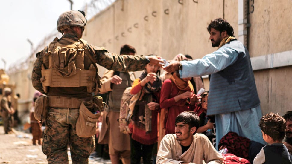 A US Marine passes out water to evacuees during an evacuation at Hamid Karzai International Airport, Kabul, Afghanistan, on 22 August 2021