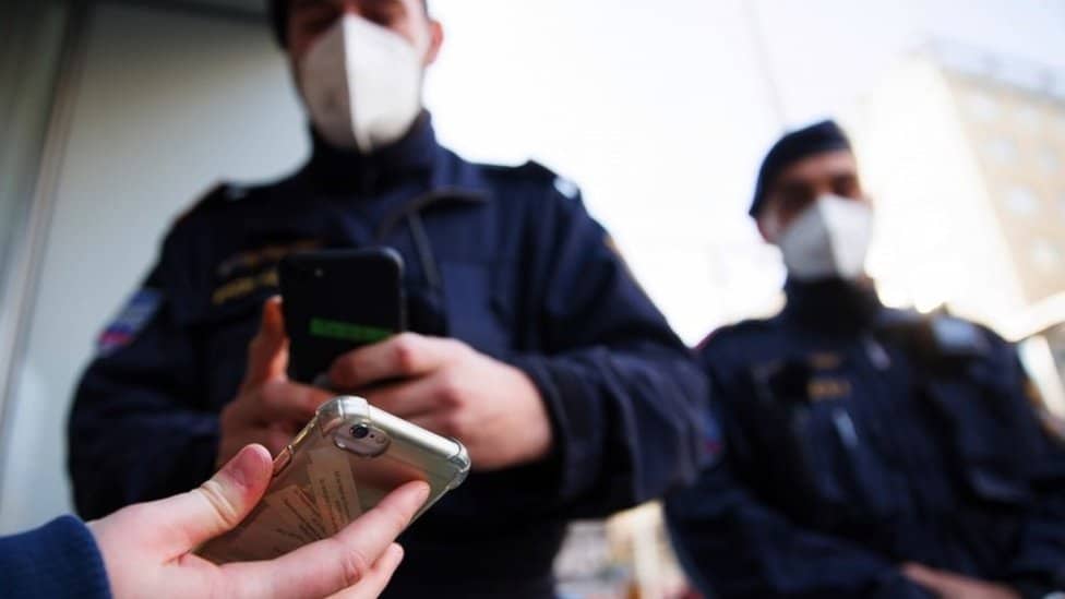 A police officer checks a vaccine status on a phone