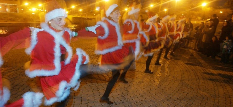 Family and friends of the community of Naperville, Naperville (Illinois, United States) celebrating the winter solstice dressed in Santa Clause outfits and dancing along the Riverwalk.