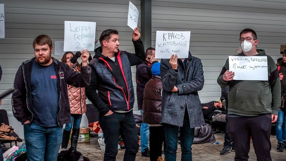 People hold up signs offering accommodation