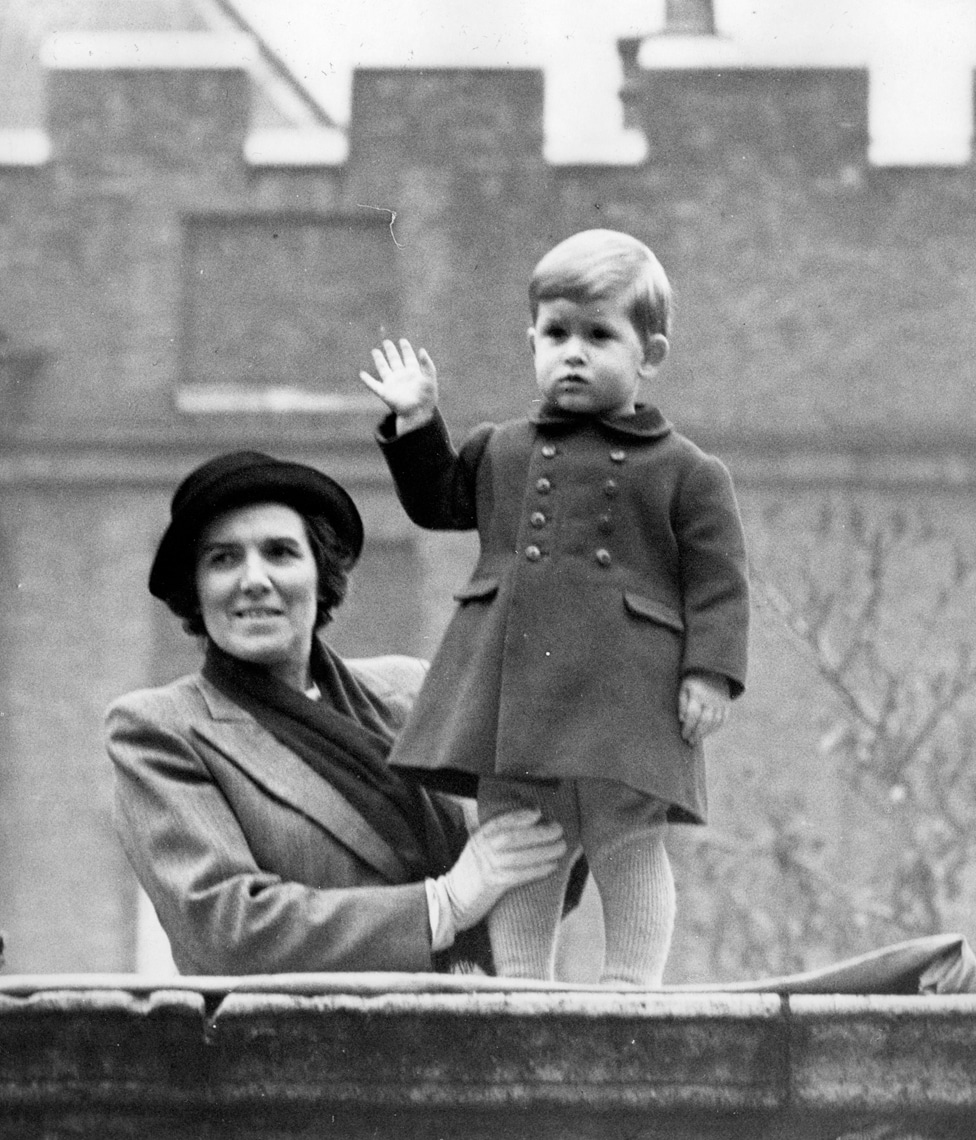 Čarls maše publici sa zida Klarens hausa u Londonu. Čvrsto ga drži medicinska sestra Lajtbodi, na vidikovcu sa kojeg je posmatrao bake i dede, kralja i kraljicu, i majku, princezu Elizabetu, kako se voze u Vestminster