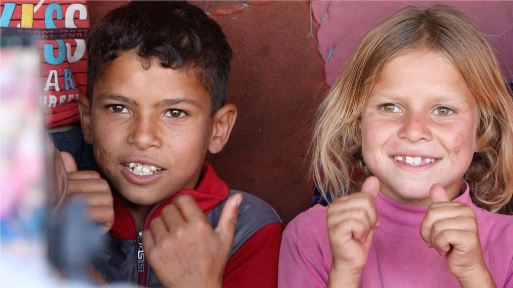 A boy and girl with the hands clenched and their thumbs raised