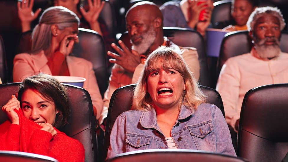 An audience reacting to a horror movie in the cinema