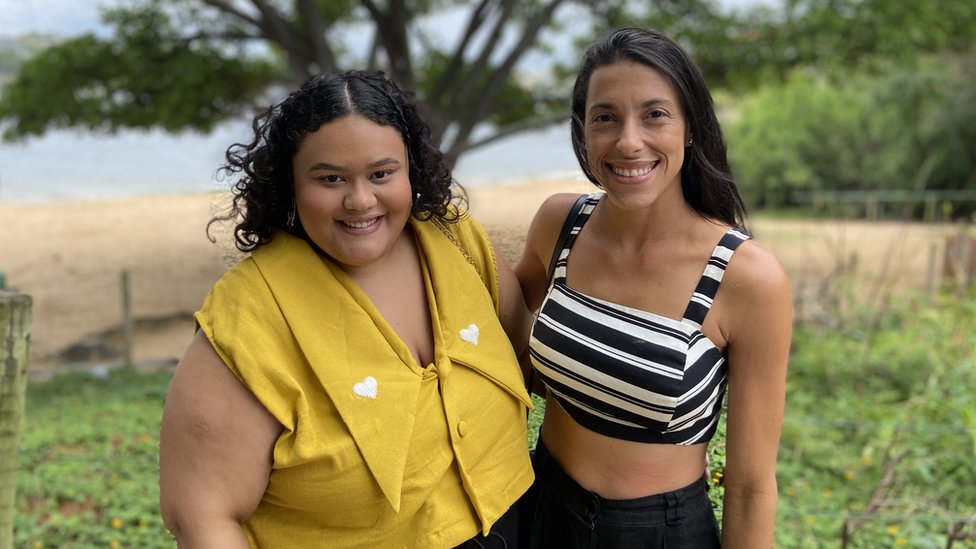 Friends Rayane and Mariana smile at the beach