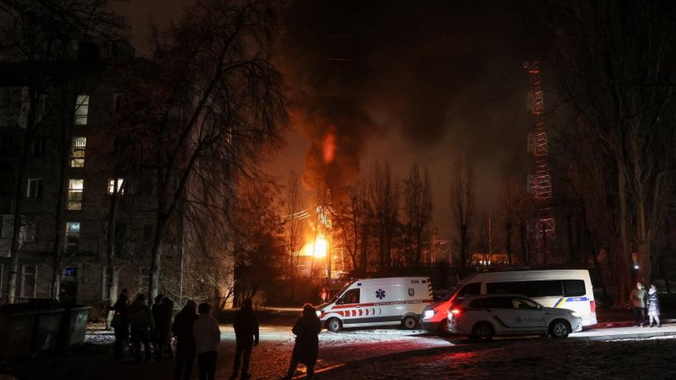 Local residents gather near a residential building as a critical power infrastructure object burns after a Russian drone attack, amid Russia's attack on Ukraine, in Kyiv, Ukraine December 19, 2022.