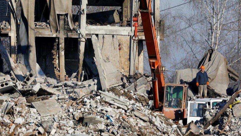 Workers remove the debris of a destroyed building