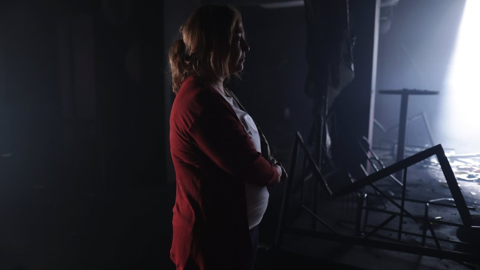 Scene of The Endless Night shows a woman looking at the scorched nightclub