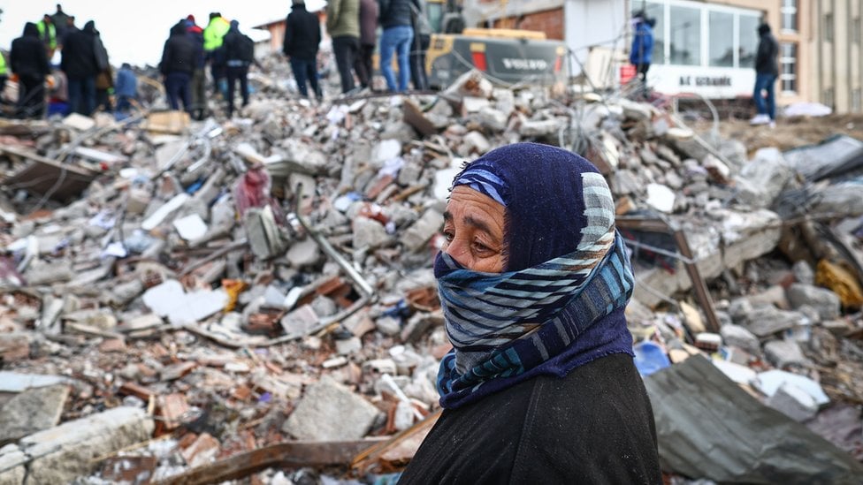 A woman looks on as emergency personnel and locals search for survivors at the site of a collapsed building in the aftermath of a major earthquake in the Elbistan district of Kahramanmaras, Turkey, 08 February 2023.