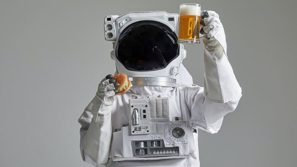 Astronaut sa burgerom i kriglom piva