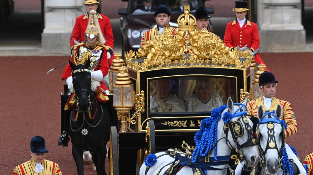 Kralja i kraljicu prate konji, muzičari i navijači koji mašu 1