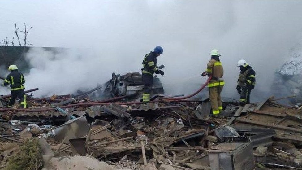 A group of emergency workers stand on top of a bombed building