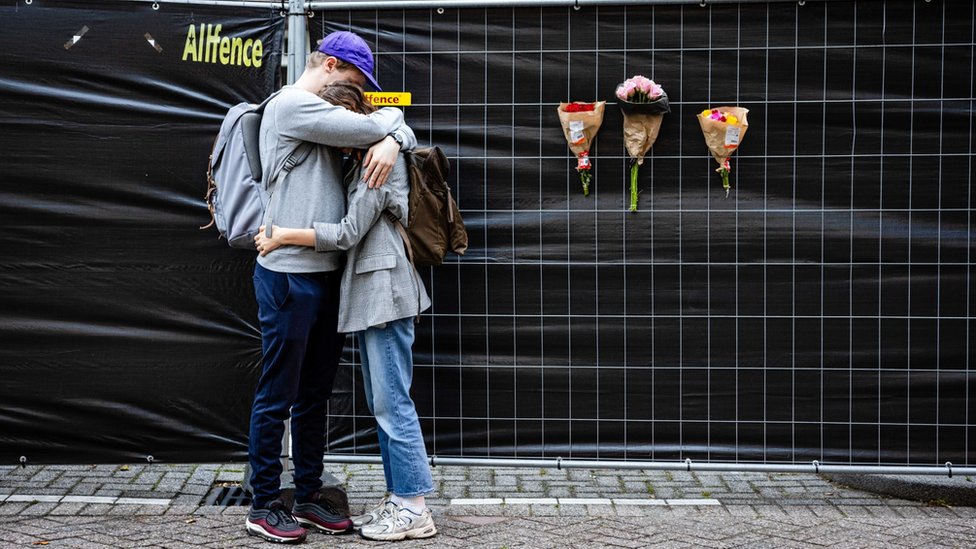A man and woman hug next to flowers left at the building where a woman and her daughter were killed in Rotterdam