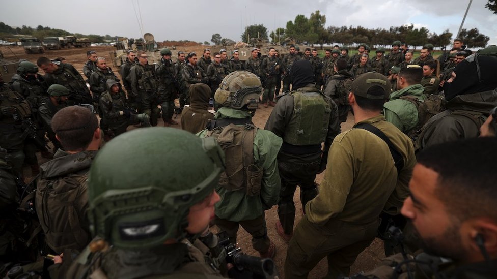 Israeli soldiers standing in a circle take part in a briefing at a position near the Gaza border, in southern Israel, 13 December 2023.