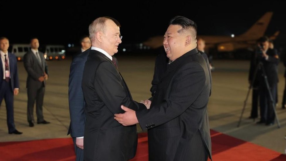President Vladimir Putin and North Korean leader Kim Jong Un greet each other on an airport runway decked out with a red carpet in Pyongyang, North Korea