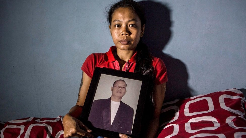 Žena iz Indoneziji drži fotografiju svoga muža, koji je umro nakon što je popio ilegalni alkohol poznat kao „oplosan"