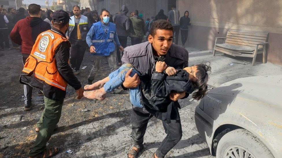 Muškarac nosi devojčicu u naručju tokom napada na Rafu, u Gazi, u novembru 2023. godine