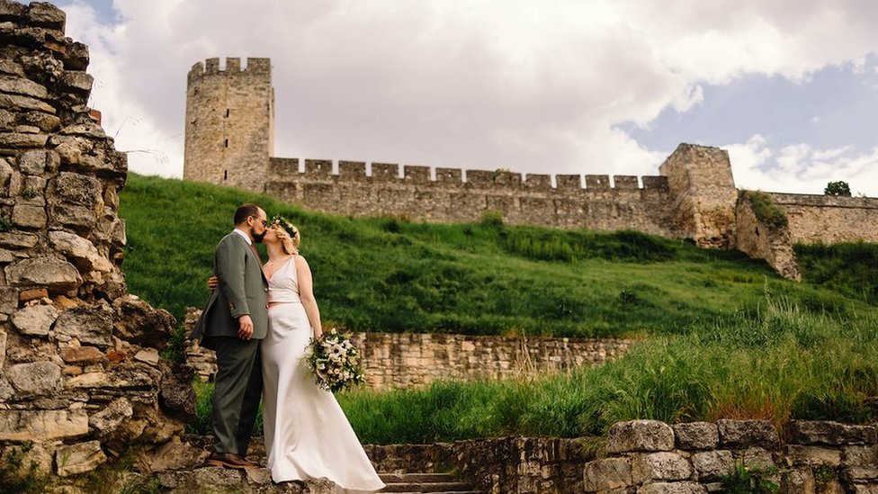 Par u odelu i venčanici se ljubi dok pozira na tvrđavi