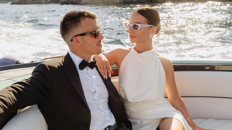 Par u odelu i venčanici pozira tokom vožnje čamcem