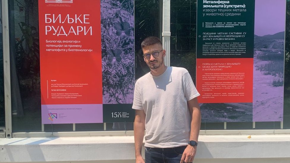 Tomica Mišljenović ispred plakata za izložbu o biljkama rudarima