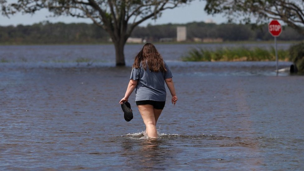 A woman walks surrounded by flood water near Lake Maggiore, after Hurricane Milton made landfall, in St. Petersburg, Florida, U.S. October 10, 2024. REUTERS/Octavio Jones