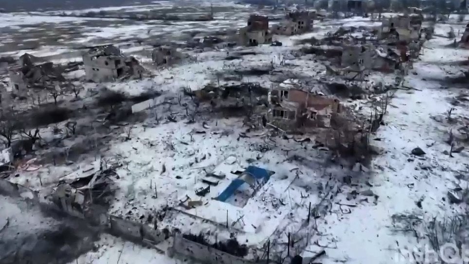 Seen from the air, Marina's damaged house and empty blue swimming pool - there is snow on the ground and other damaged building nearby.