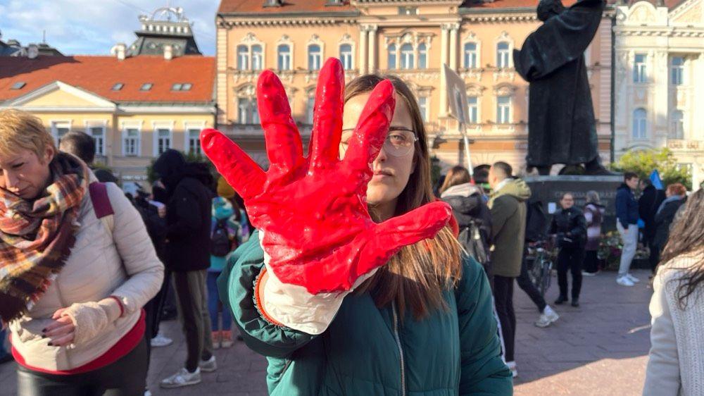 Jedna od učesnica protesta pokazuje šaku ofarbanu crvenom bojom 