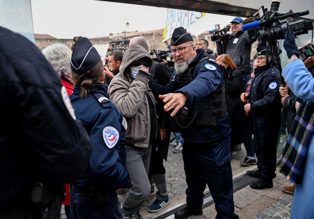 Jedan od optuženika stiže u sudnicu pokrivenog lica sa kapuljačom na glavi okružen policajcima