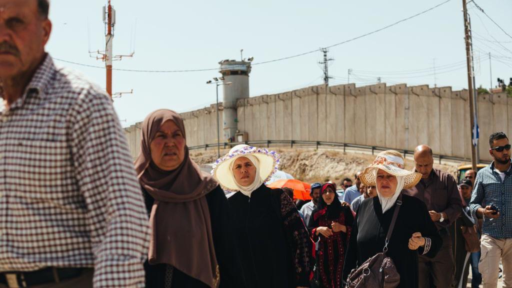 Palestinci stoje u redu na prelazu Kalandija, južno od Ramale na Zapadnoj obali, iza njih je zid