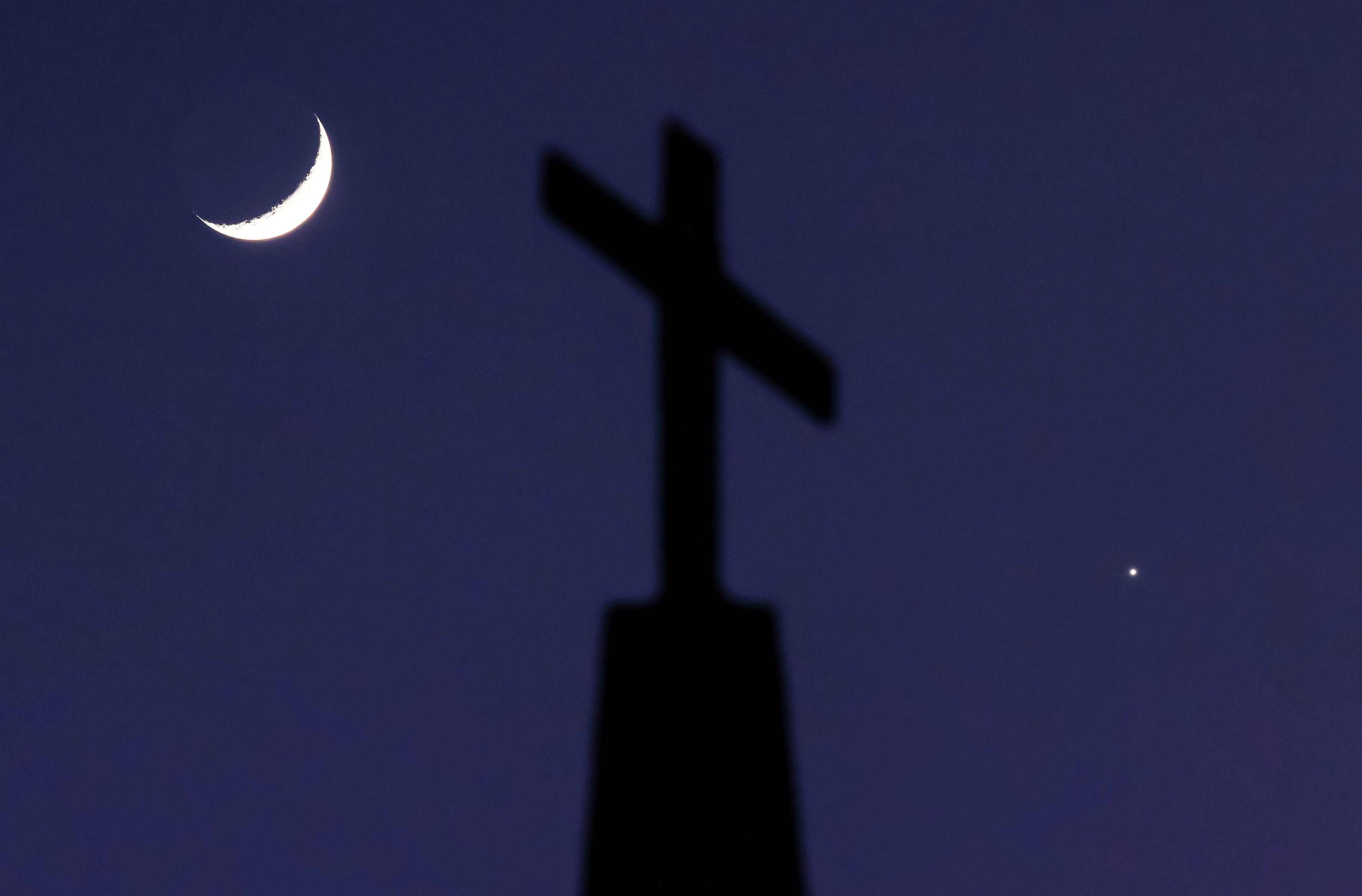 A crescent moon and the planet Venus straddle a cross on top of Quebec Baptist Church in Ellaville, Georgia